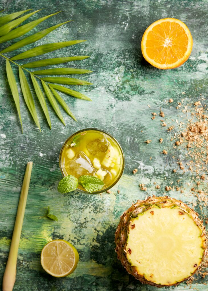 frutas cítricas, vaso de zumo y fondo verde