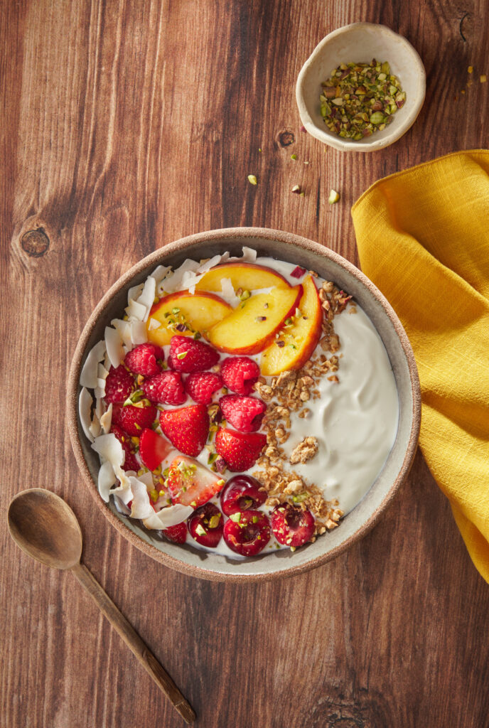 bowl de yogur, frutas y granola sobre fondo de madera